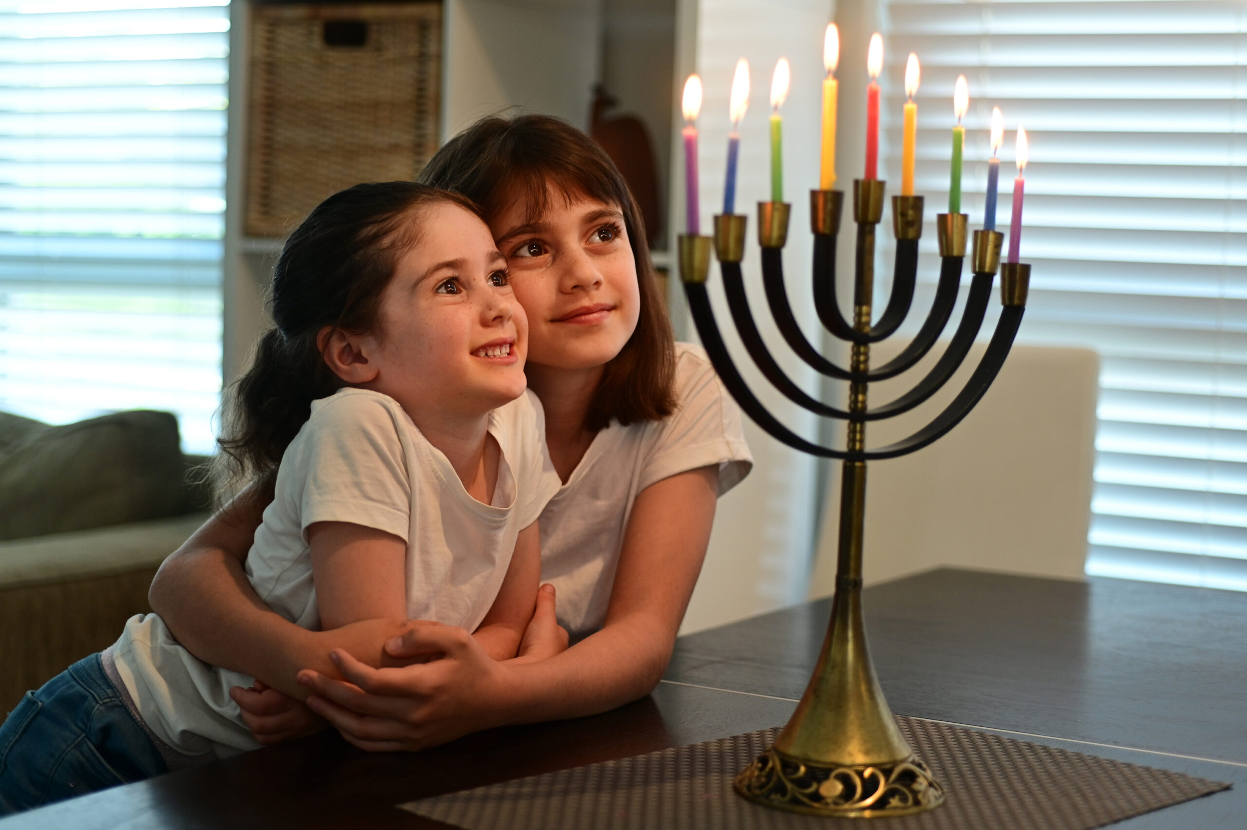 Jewish sisters looking at a beautiful menorah candelabra on Hanukkah Jewish holiday
